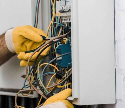 Zwei Hände an einem Stromkasten mit mehreren Kabel